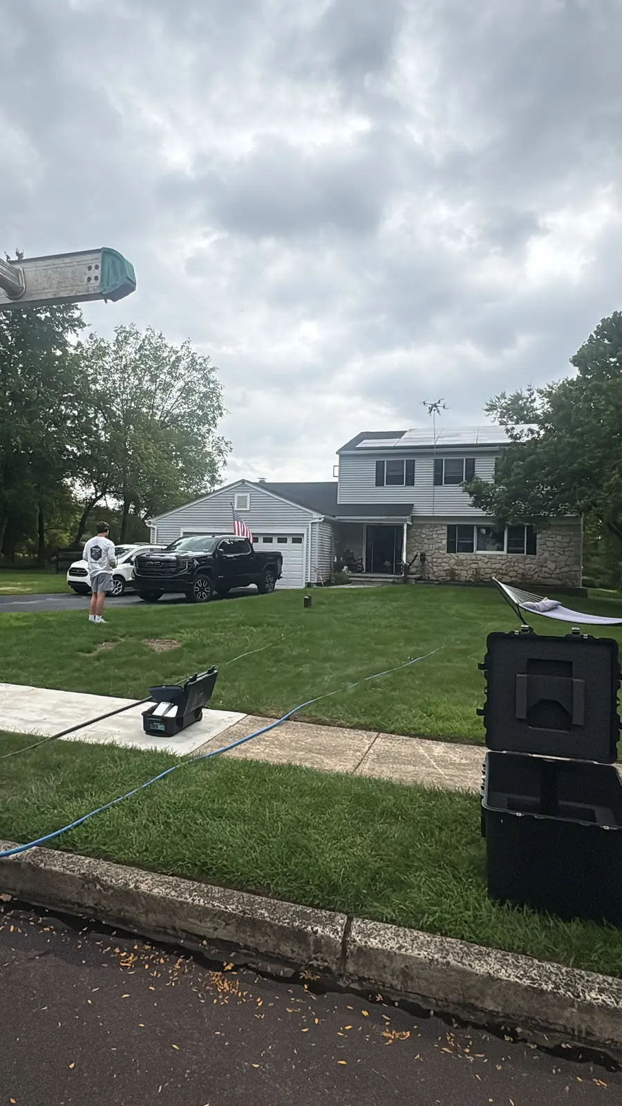 Drone and hose set up on the front lawn of a home with rooftop solar panels