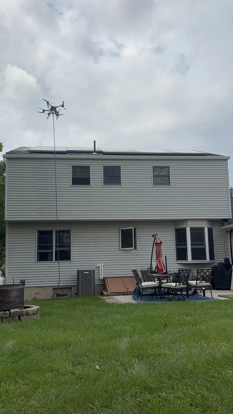 Cleaning drone above a two-story home with a rooftop solar array